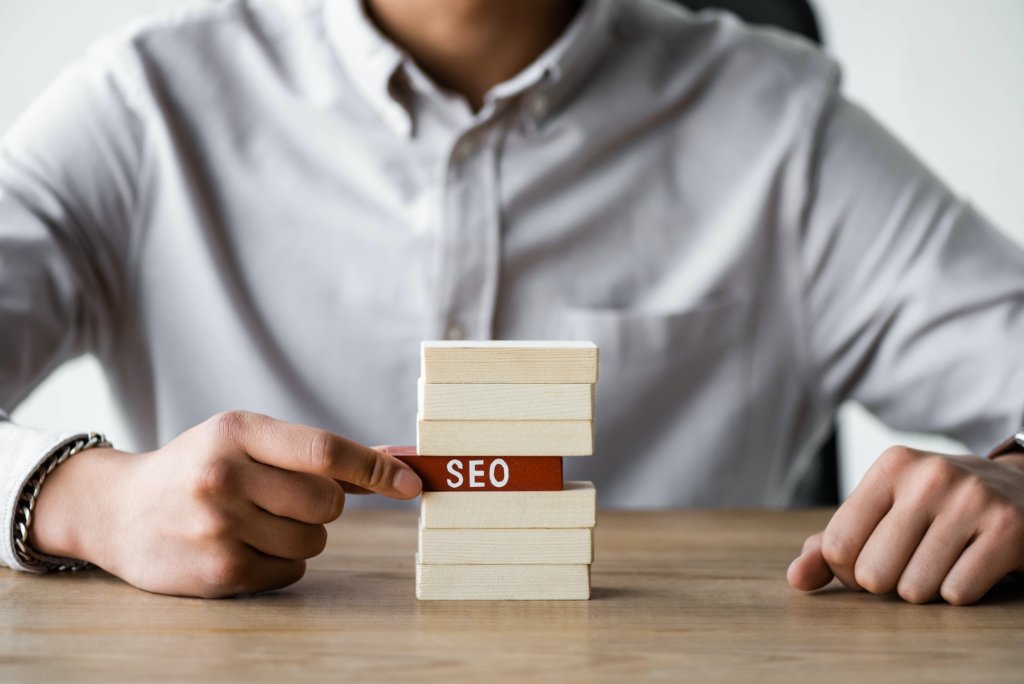 cropped view of seo manager holding wooden rectangle with lettering seo