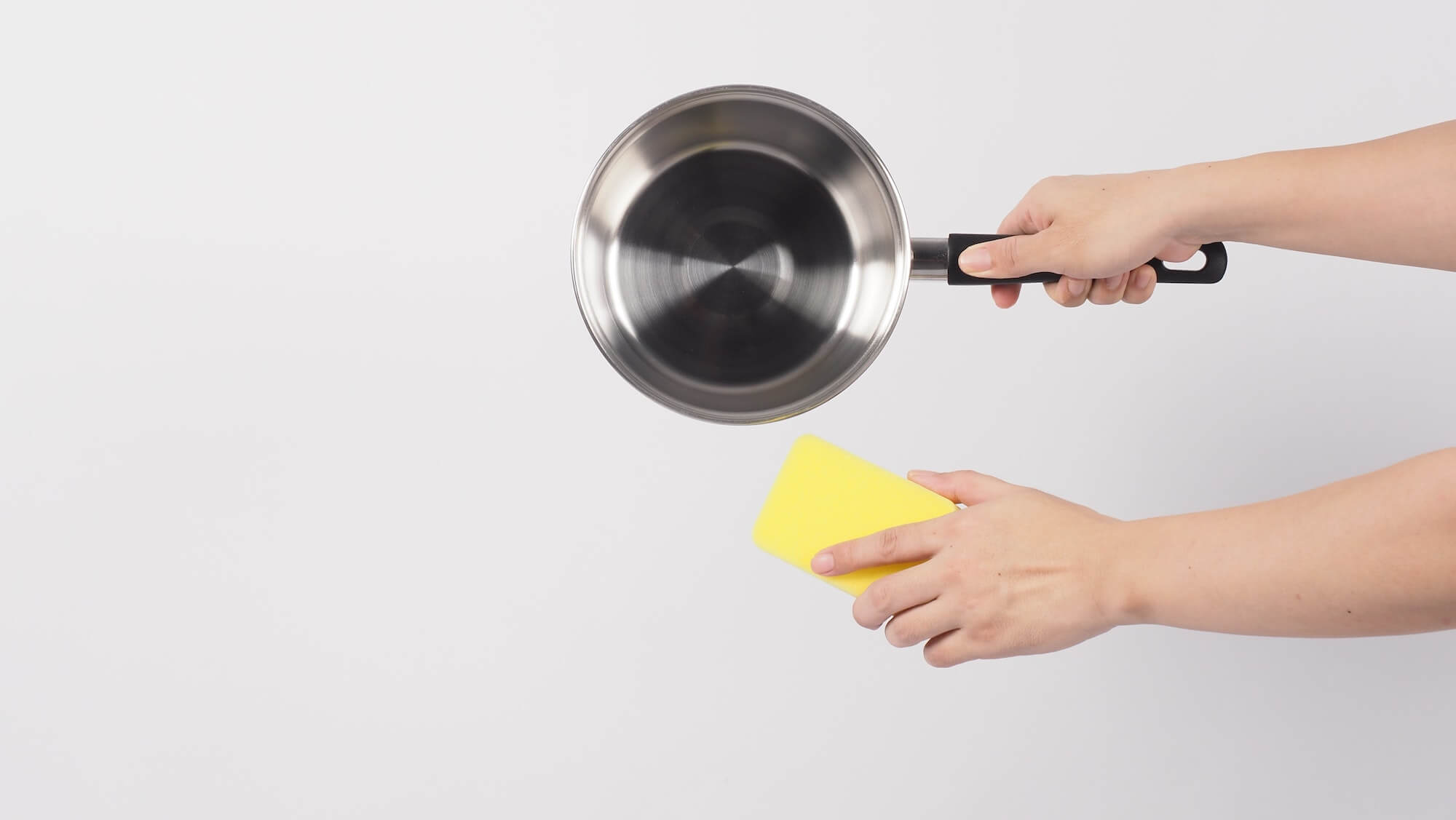 Pot cleaning. Man hand on white background cleaning the non stick pot with handy dish washing sponge